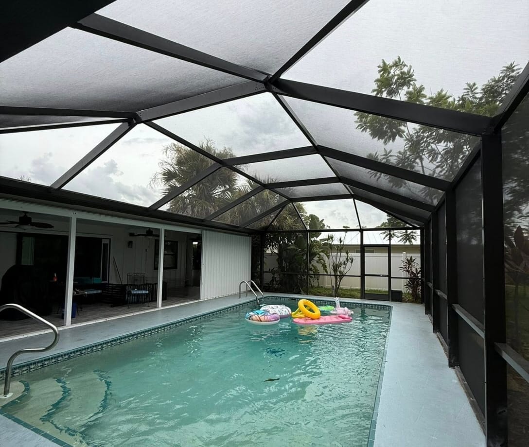 Inside view of a modern aluminum pool enclosure under clear blue sky